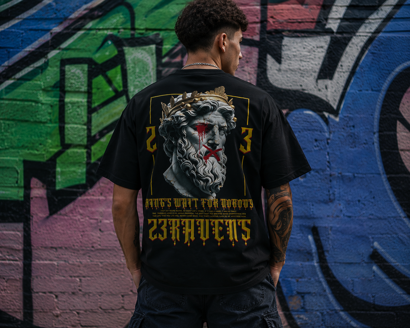 Back view of model wearing black 23Ravens oversized t-shirt with gothic graphic print in urban street setting