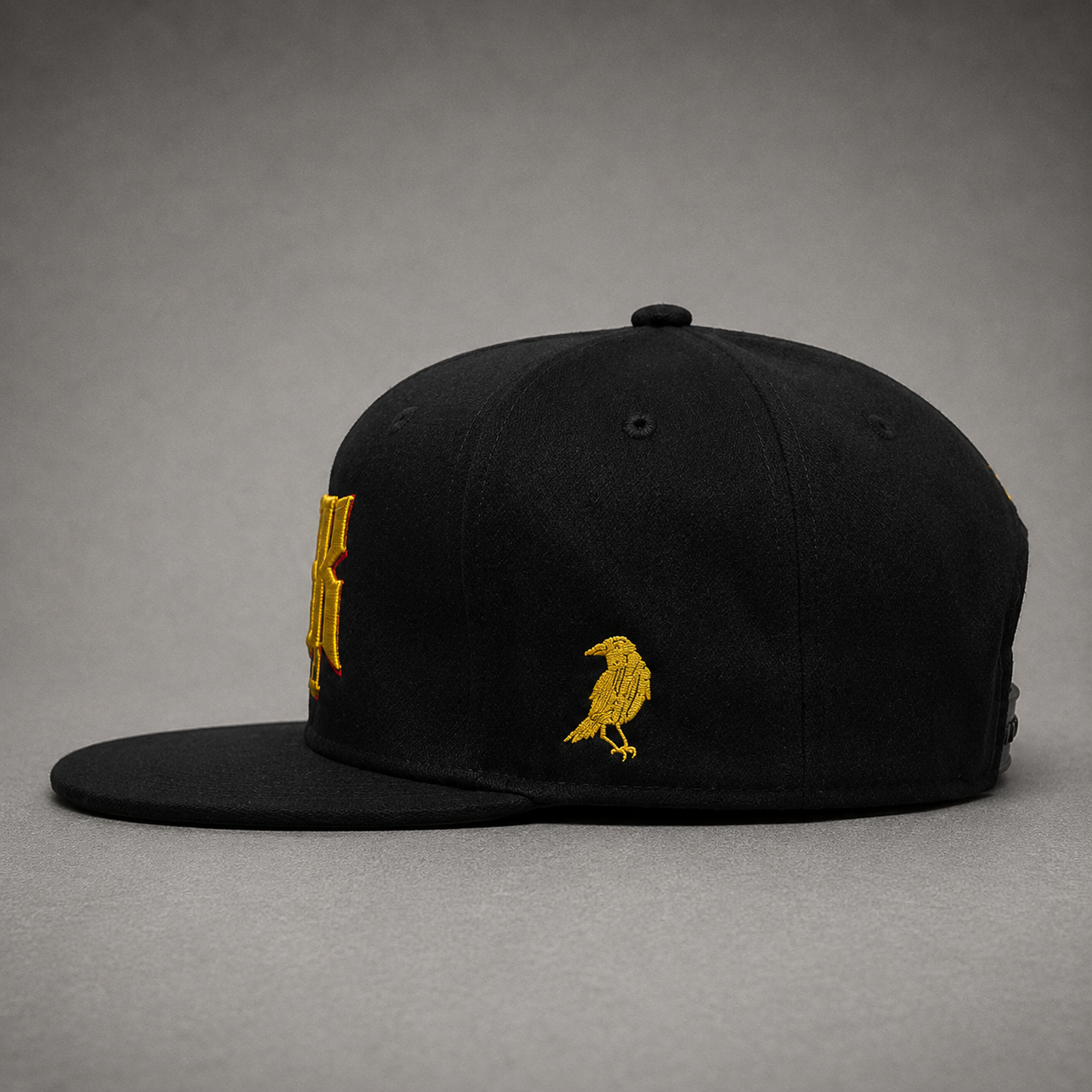 Side view of black 23Ravens snapback cap featuring embroidered gold raven logo